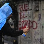 Un manifestante scrive su un muro "E' stato lo Stato", in relazione alla scomparsa degli studenti