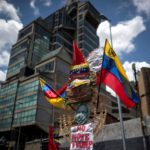 Tra le bandiere del Venezuela, compare un cartello con scritto "Basta con Donald Trump" Tra le bandiere del Venezuela, compare un cartello con scritto "Basta con Donald Trump"