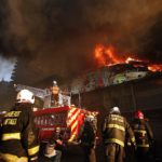 I pompieri domano uno dei numerosi incendi appiccati a Santiago