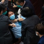 Il deputato pan-democratico Wu Chi-wai viene portato fuori dagli agenti di sicurezza