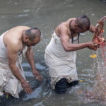 Due preti immergono un idolo nel fiume