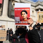 Una donna mostra una foto di Aung San Suu Kyi durante le proteste fuori dal Parlamento a Londra