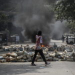 Un ragazzo cammina tra le barricate durante gli scontri a Yangon