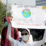 Una manifestante a Giacarta invita con un cartellone a salvare il nostro pianeta