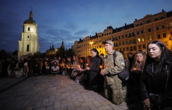 Persone in ginocchio nel corso della manifestazione in memoria delle vittime del centro di Olenivka