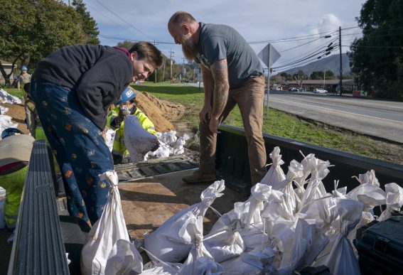 Alcuni abitanti sollevano sacchi di sabbia preparati dal California Conservation Corps