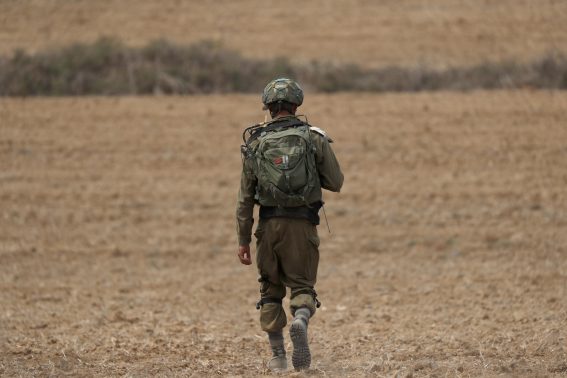 Un soldato israeliano pattuglia un campo poco a sud di Gaza.