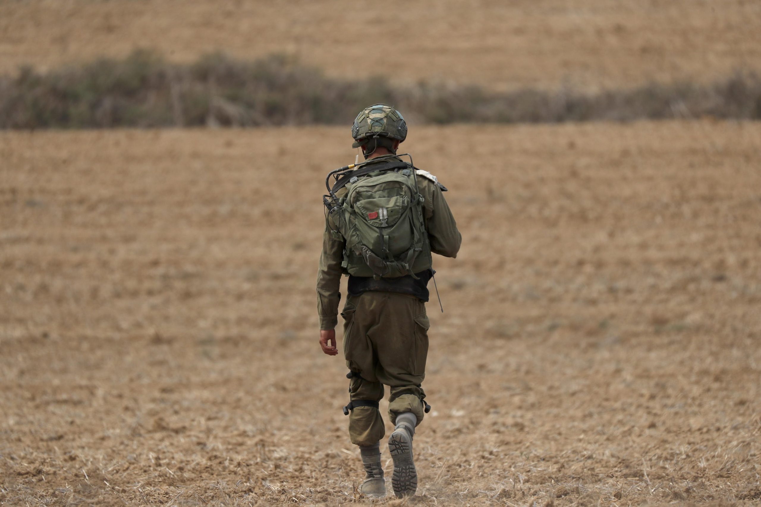 Un soldato israeliano pattuglia un campo poco a sud di Gaza.