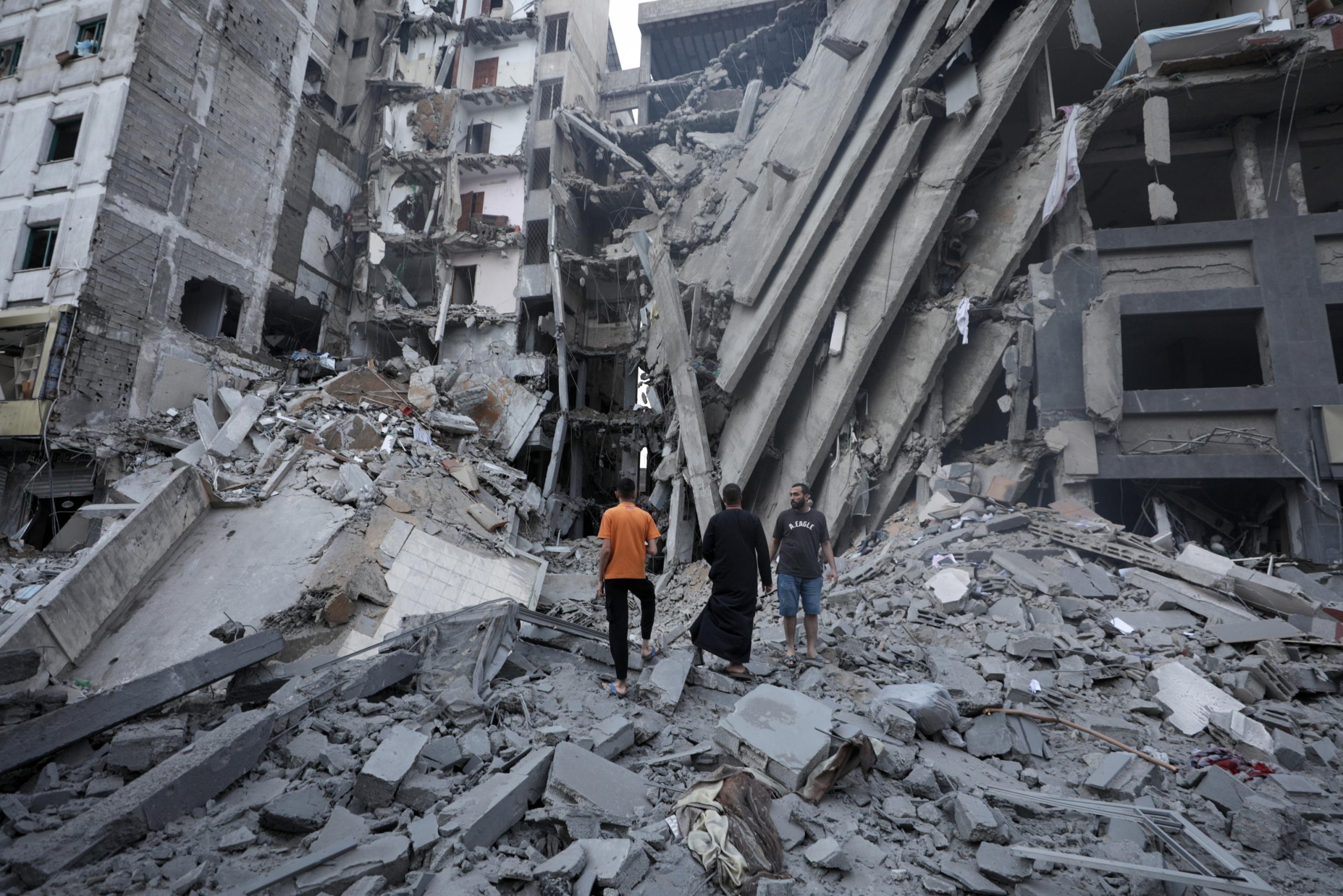 Alcuni palestinesi osservano le macerie della Banca Nazionale di Gaza, distrutta dai bombardamenti israeliani.