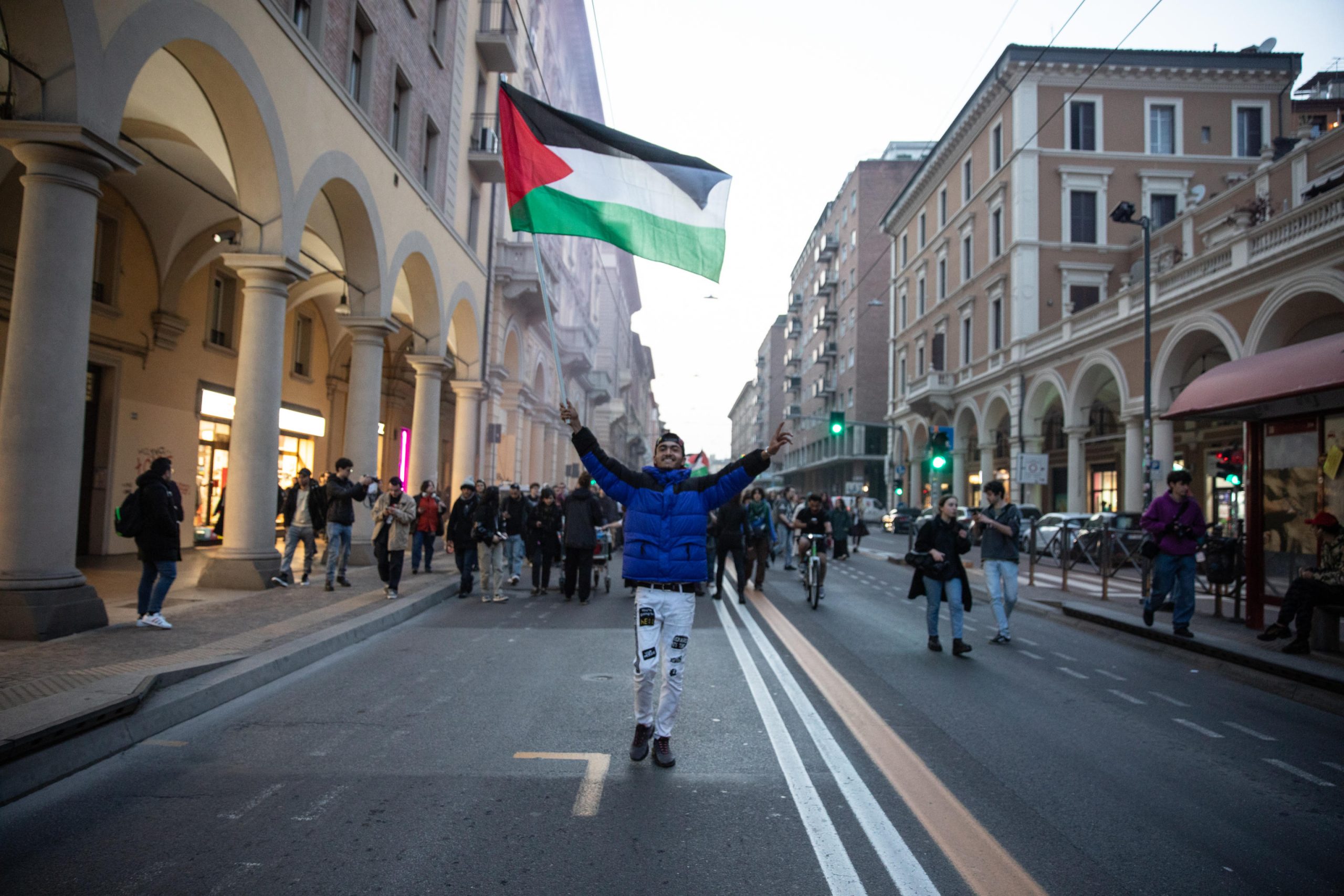 Un manifestante mentre sventola la bandiera della Palestina, nel corteo a Bologna.
