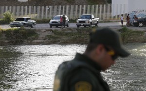 Agenti del United States Border Patrol stanno sulle due rive del Rio Grande, quella statunitense (in primo piano) e quella messicana.